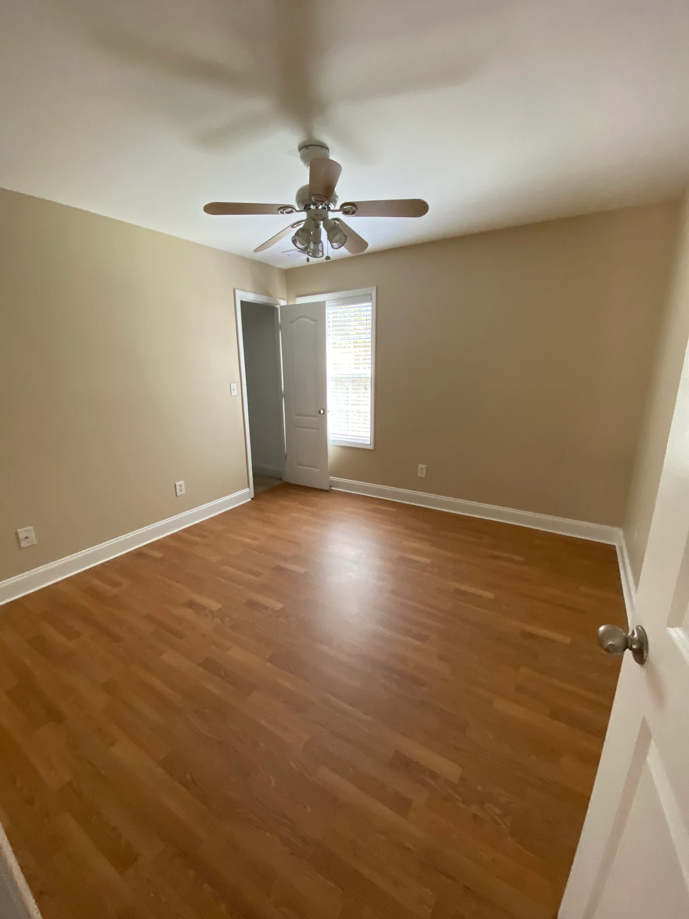 Customer photo: bedroom with warm wood-tone flooring, neutral walls, and white trim