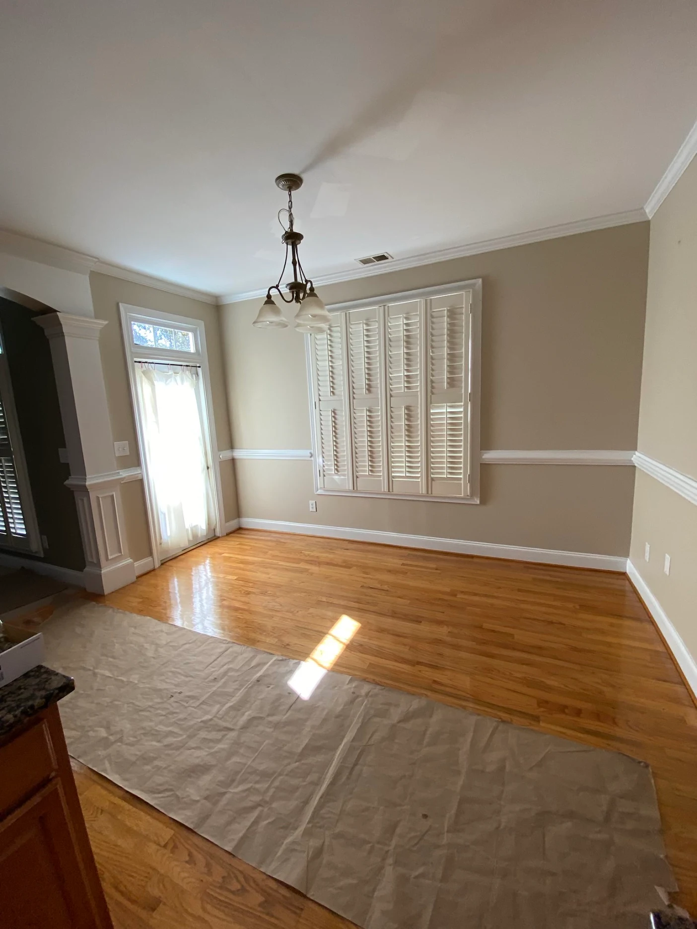 Customer photo: glossy wood-tone flooring in a dining room, with protective covering along the work path